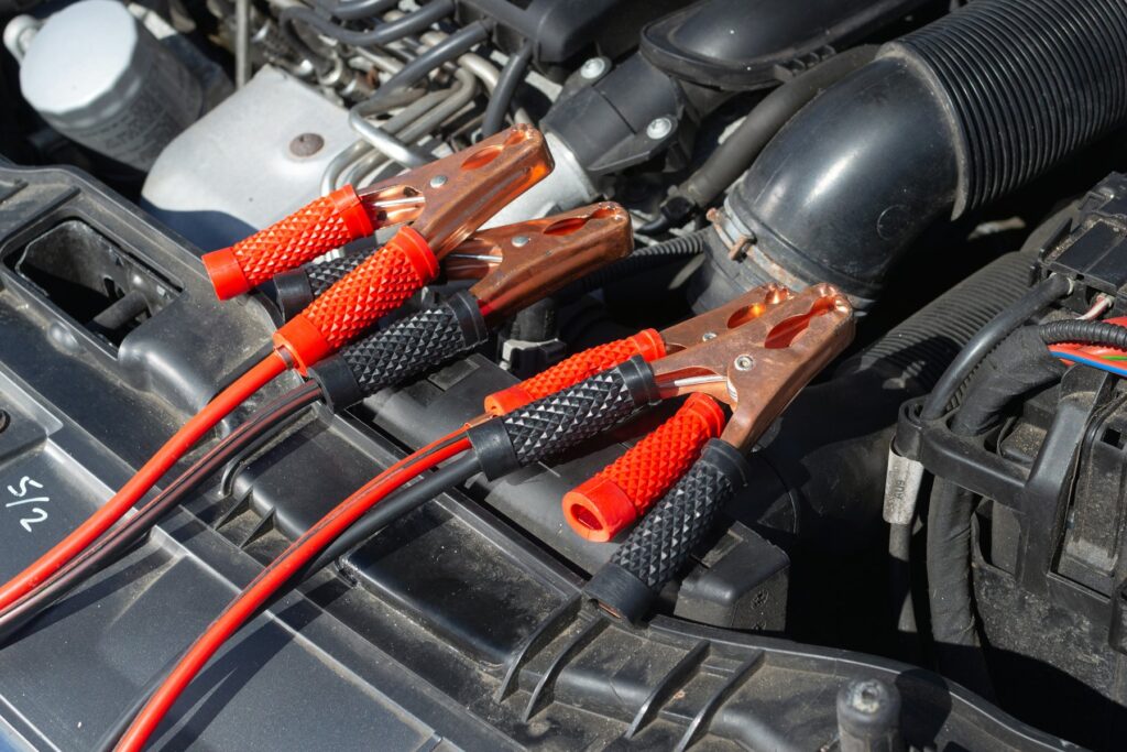 Jumper leads clamped to a car battery in an engine bay