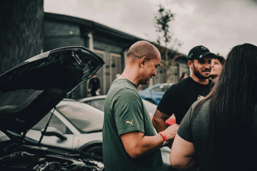 Mechanic talking customers through a car with the bonnet open